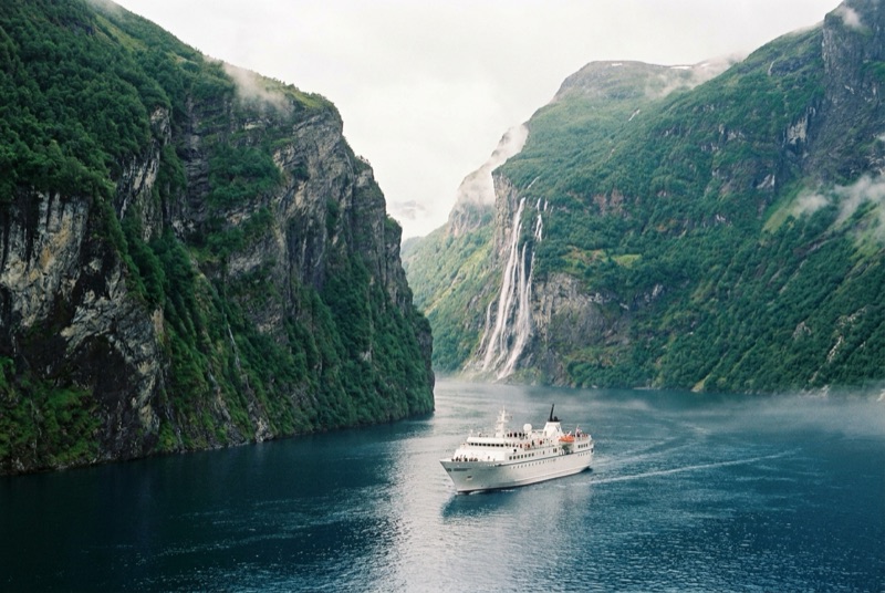 Crucero navegando por un fiordo noruego con cascada y montañas